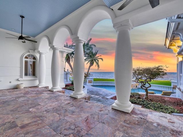 patio terrace at dusk with ceiling fan and a water view