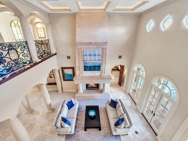 living room with french doors, a towering ceiling, decorative columns, ornamental molding, and coffered ceiling