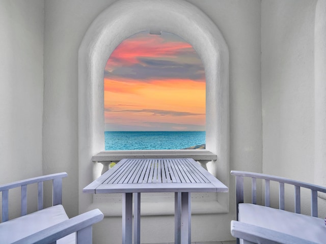 balcony at dusk featuring a water view