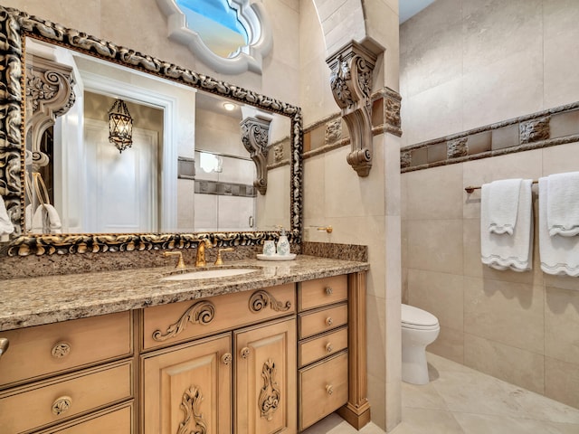 bathroom with tile patterned floors, vanity, tile walls, and toilet