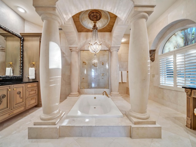 bathroom with tiled bath, a wealth of natural light, vanity, and a chandelier