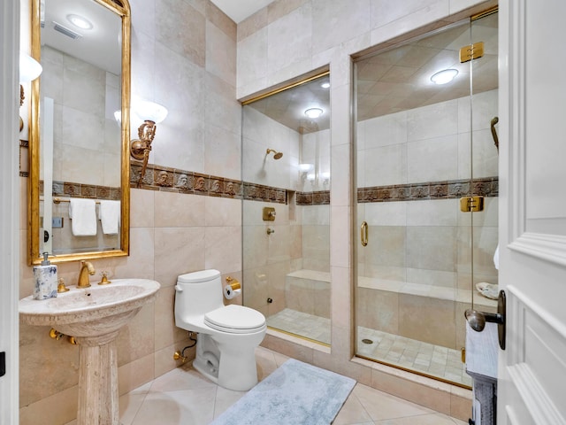 bathroom with tile patterned flooring, toilet, an enclosed shower, and tile walls