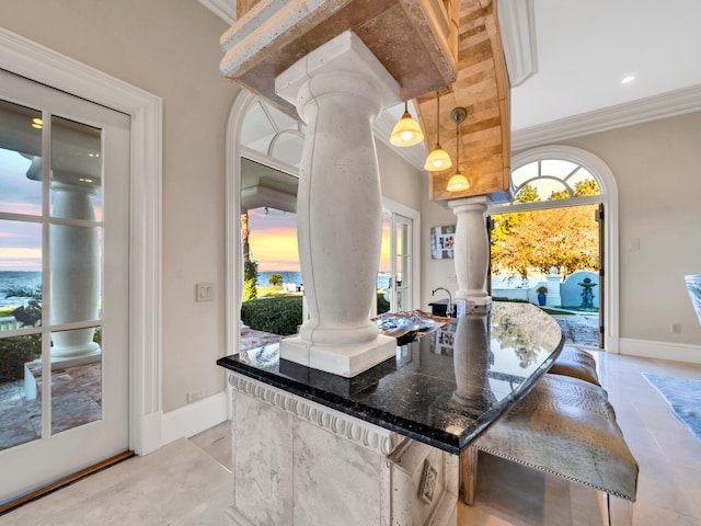 bar featuring pendant lighting, decorative columns, crown molding, and dark stone countertops