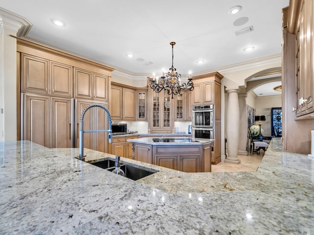 kitchen with decorative light fixtures, a kitchen island, ornamental molding, and sink