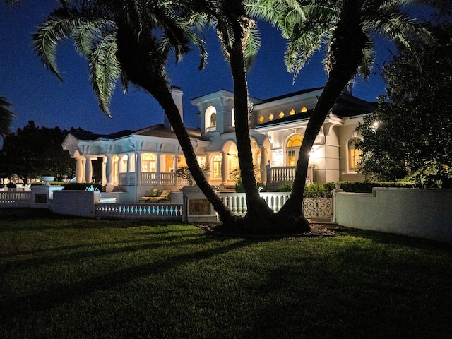 back house at twilight featuring a lawn