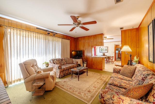 living room with wood walls, ceiling fan, and a wealth of natural light