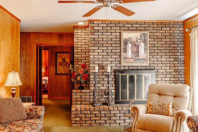 carpeted living room featuring a brick fireplace, wooden walls, and ceiling fan