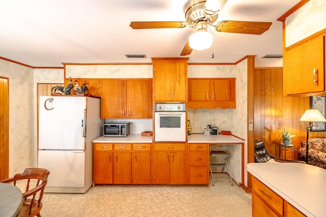 kitchen with wooden walls, white appliances, ceiling fan, and crown molding