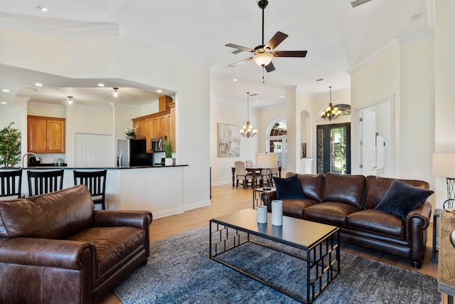 living room with ornamental molding, ceiling fan with notable chandelier, and light hardwood / wood-style floors