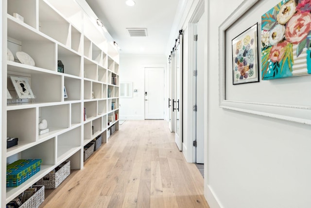 corridor with a barn door and light wood-type flooring