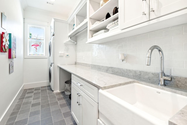 laundry room with stacked washing maching and dryer, ornamental molding, and sink