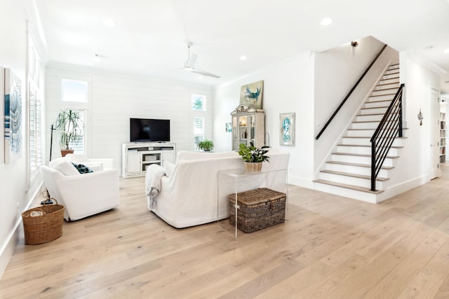 living room featuring ceiling fan, a healthy amount of sunlight, ornamental molding, and light hardwood / wood-style flooring