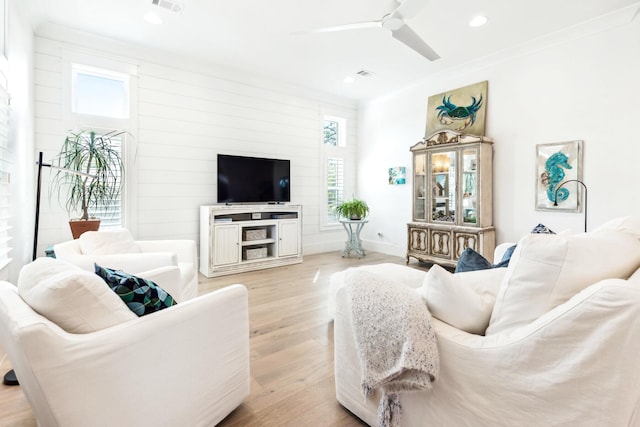 living room with a wealth of natural light, crown molding, light wood-type flooring, and ceiling fan