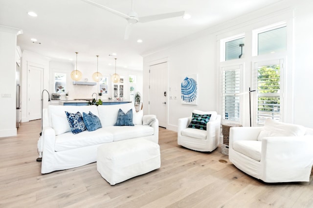 living room featuring ornamental molding, light hardwood / wood-style floors, and ceiling fan