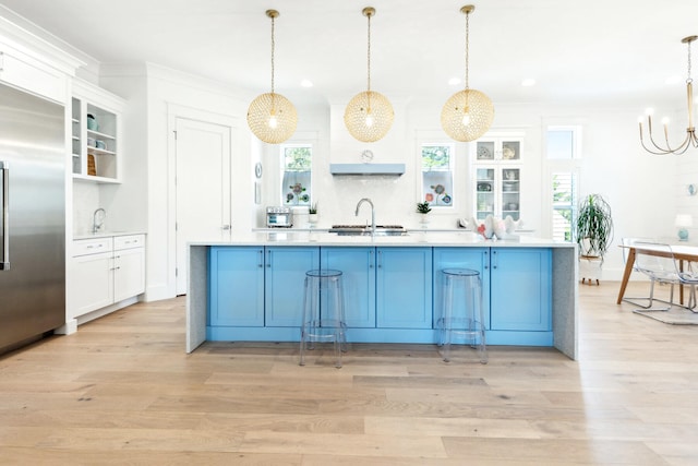 kitchen with blue cabinetry, light hardwood / wood-style flooring, decorative light fixtures, and stainless steel built in refrigerator