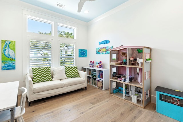 sitting room featuring ceiling fan, ornamental molding, and light wood-type flooring