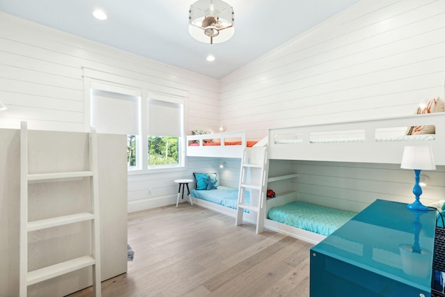 bedroom featuring light hardwood / wood-style flooring, wood walls, and lofted ceiling