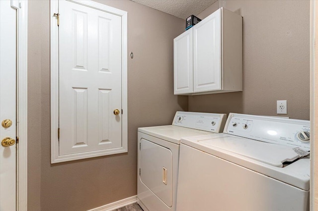 washroom with washer and dryer, cabinets, and a textured ceiling