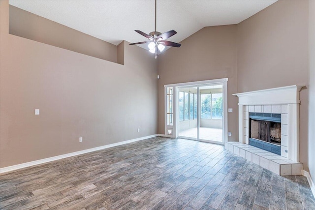 unfurnished living room featuring high vaulted ceiling, ceiling fan, hardwood / wood-style floors, a tiled fireplace, and a textured ceiling