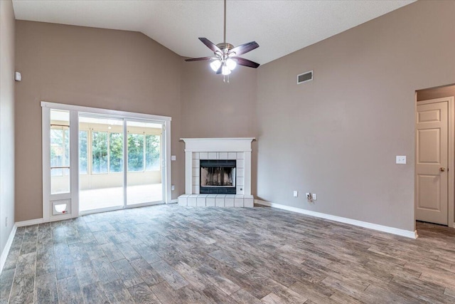 unfurnished living room with ceiling fan, a textured ceiling, a tiled fireplace, high vaulted ceiling, and hardwood / wood-style floors