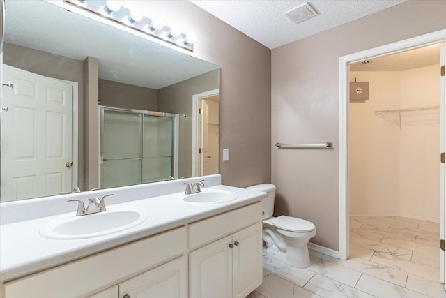 bathroom featuring vanity, a textured ceiling, toilet, and an enclosed shower