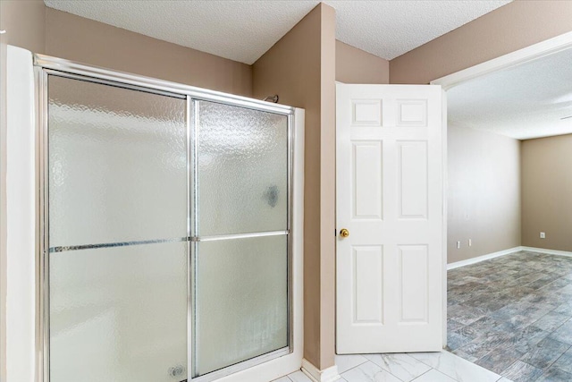 bathroom with a shower with shower door and a textured ceiling