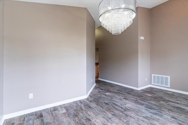 spare room featuring dark hardwood / wood-style floors and an inviting chandelier