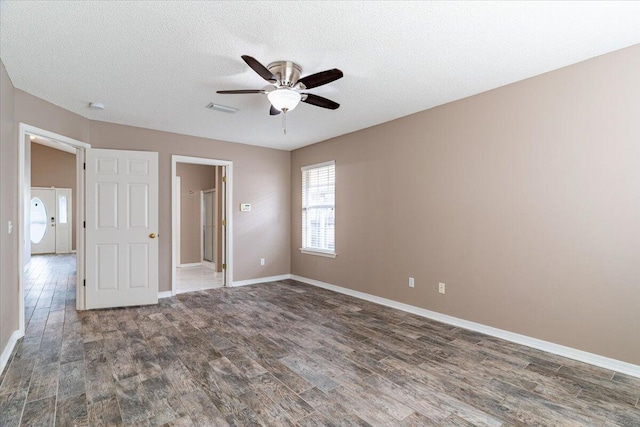 unfurnished room featuring ceiling fan, dark hardwood / wood-style floors, and a textured ceiling