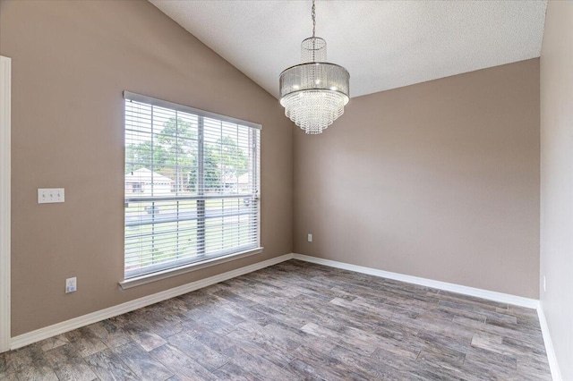 empty room with wood-type flooring, vaulted ceiling, a chandelier, and a textured ceiling