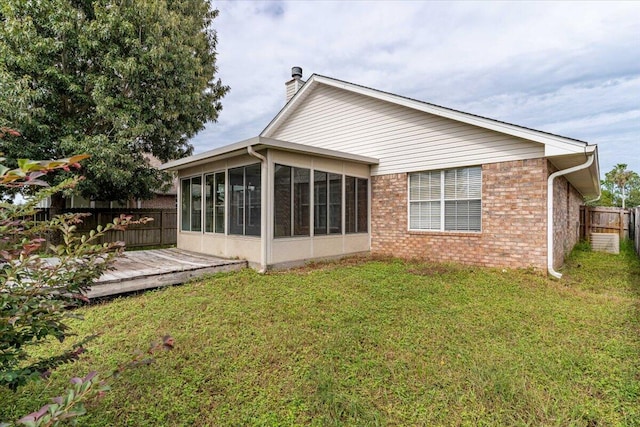 back of property with a sunroom, a yard, and a wooden deck