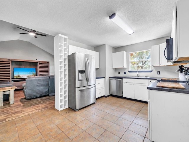 kitchen featuring ceiling fan, white cabinetry, vaulted ceiling, and stainless steel appliances