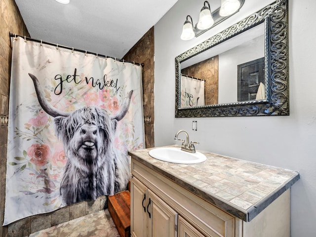 bathroom with curtained shower, vanity, and a textured ceiling