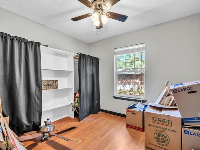 misc room with light hardwood / wood-style flooring, a textured ceiling, and ceiling fan