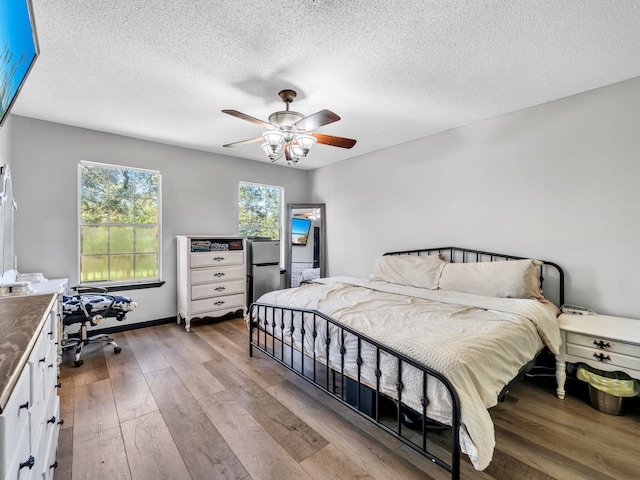 bedroom with light hardwood / wood-style floors, a textured ceiling, and ceiling fan