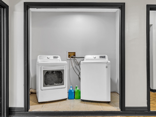 clothes washing area with light tile patterned floors and washer and clothes dryer