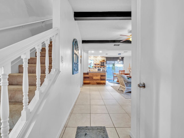 stairway featuring ceiling fan, tile patterned flooring, and beam ceiling