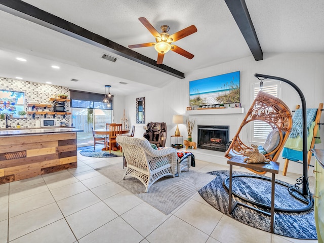 tiled living room featuring ceiling fan, lofted ceiling with beams, and a textured ceiling