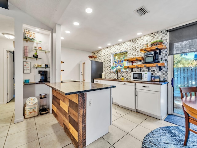 kitchen with tasteful backsplash, white cabinets, white appliances, kitchen peninsula, and light tile patterned floors