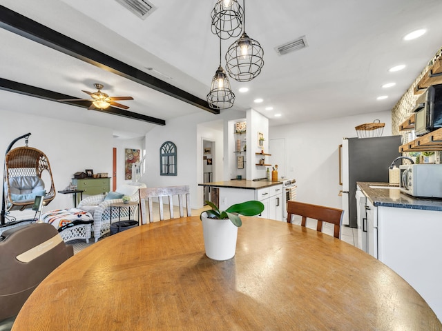 dining space with ceiling fan, beamed ceiling, and light hardwood / wood-style floors