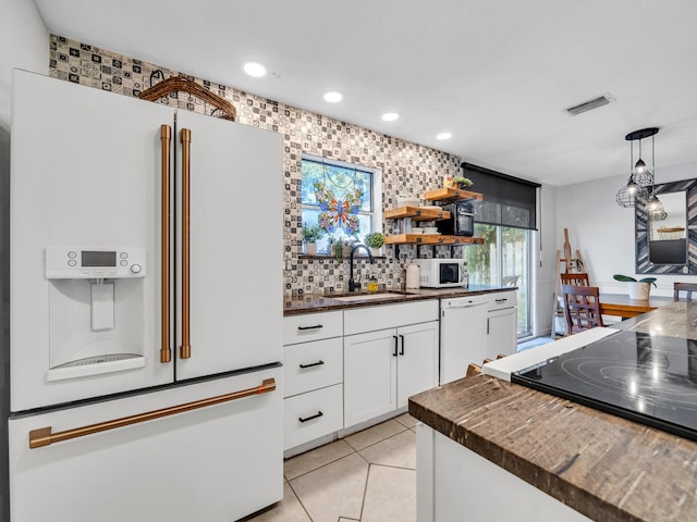 kitchen featuring tasteful backsplash, white appliances, sink, light tile patterned floors, and white cabinetry