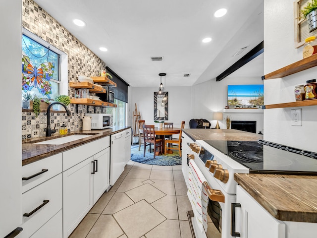 kitchen with white cabinets, pendant lighting, light tile patterned floors, sink, and white appliances