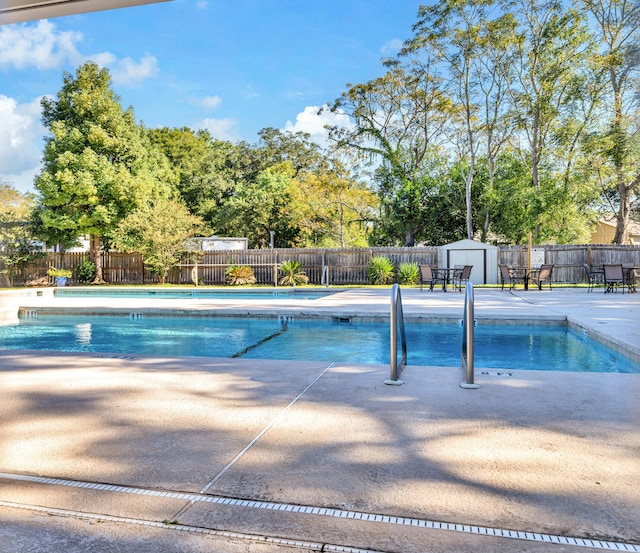 view of swimming pool featuring a storage shed and a patio area