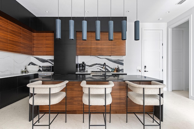 kitchen with a kitchen breakfast bar, backsplash, pendant lighting, and a kitchen island