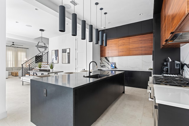 kitchen with premium range hood, ceiling fan, decorative light fixtures, a center island with sink, and sink