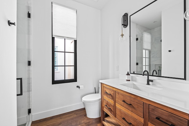 bathroom featuring hardwood / wood-style floors, vanity, a shower with shower door, and toilet