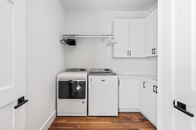 laundry area with cabinets, dark hardwood / wood-style floors, and washing machine and dryer