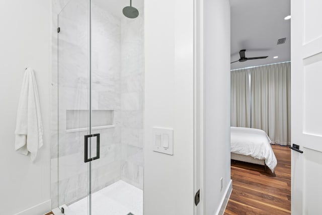 bathroom featuring hardwood / wood-style floors, ceiling fan, and a shower with shower door