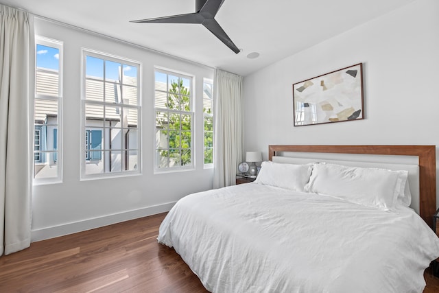 bedroom with multiple windows, dark hardwood / wood-style flooring, and ceiling fan