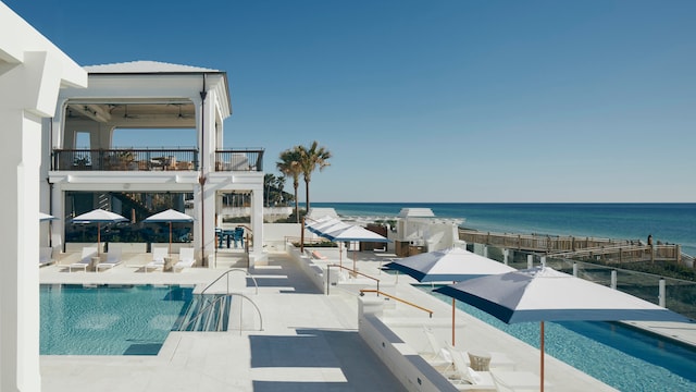 view of swimming pool with ceiling fan, a patio, and a water view