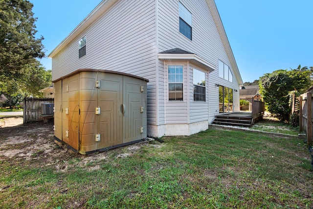 back of property with central AC unit, a yard, and a deck